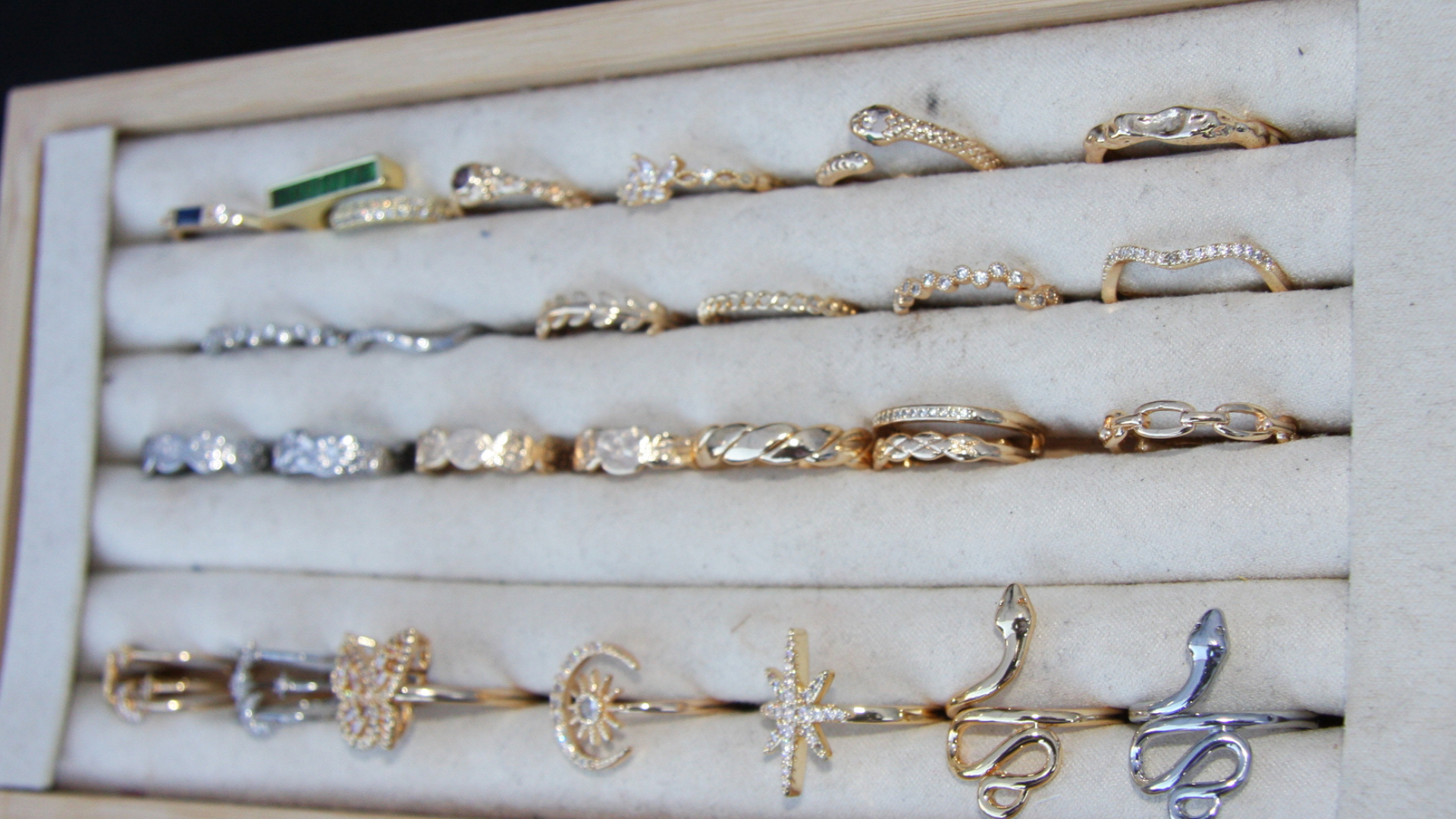 Rows of gold and silver rings displayed on a velvet tray, featuring designs like snakes, stars, moons, and eternity bands.