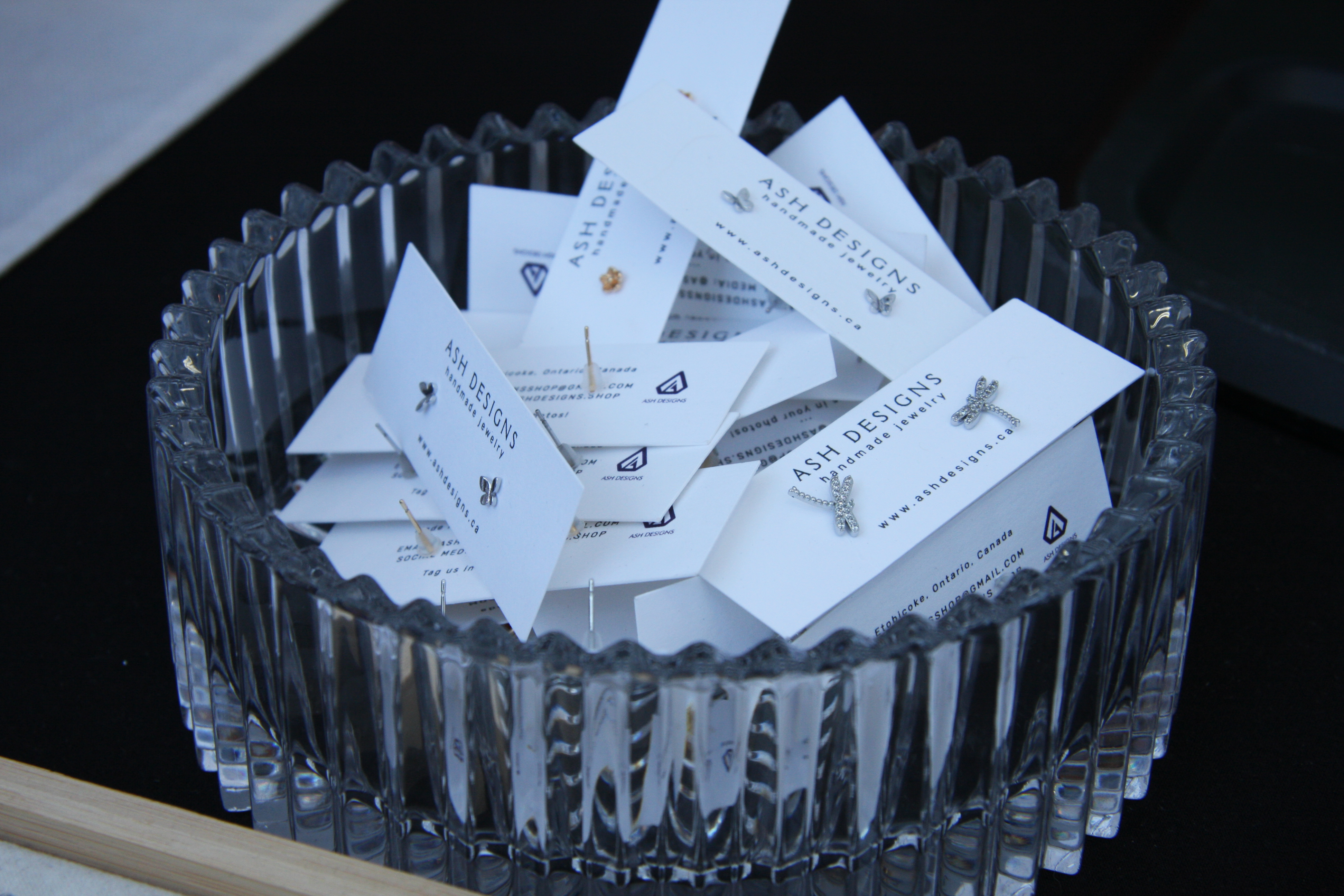 Ash Designs single stud earrings, shaped like butterflies and dragonflies, displayed on cards inside a glass bowl