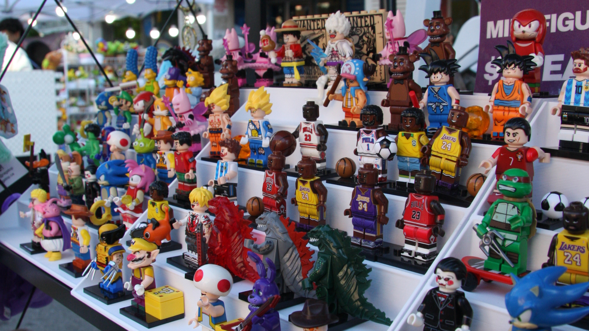 Rows of collectible minifigures displayed at a market stall, including sports stars, anime characters, and pop-culture icons.